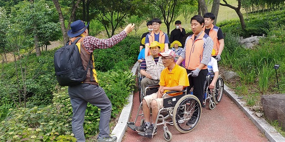휠체어를 타고있는 이용자들과 휠체어를 밀어주고 있는 관계자들의 모습